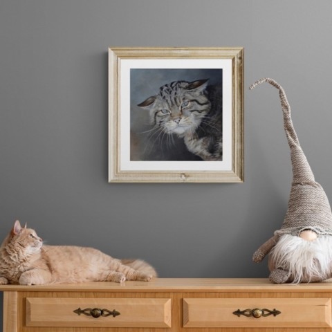 European wildcat portrait painting wall art decor in a setting above a sideboard with a cat lying down by wildlife artist Laurence Saunois