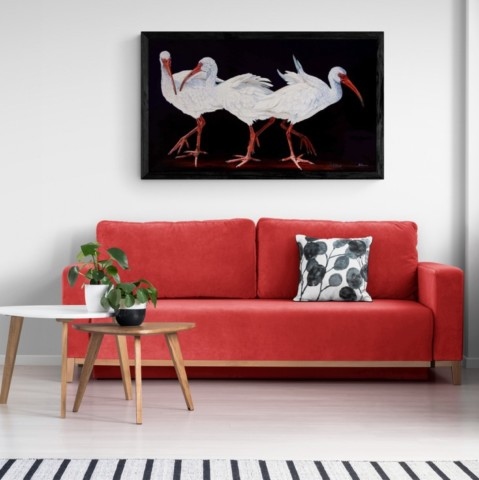 Tableau d'ibis blancs dans un salon au dessus d'un canapé rouge