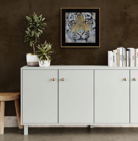 Young tiger portrait painting wall art decor in a living room setting above a white piece of furniture by wildlife artist Laurence Saunois
